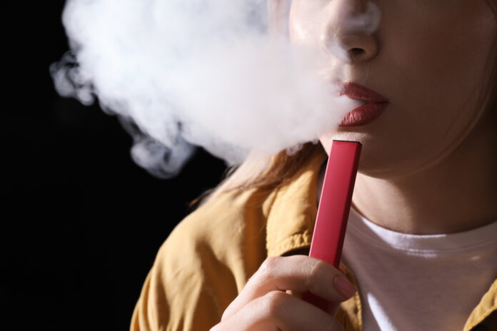 Young woman using electronic cigarette on black background, closeup sigarette elettroniche